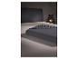 Donkergrijs hoeslaken op een bed met een donker hoofdbord en decoratieve lamp.