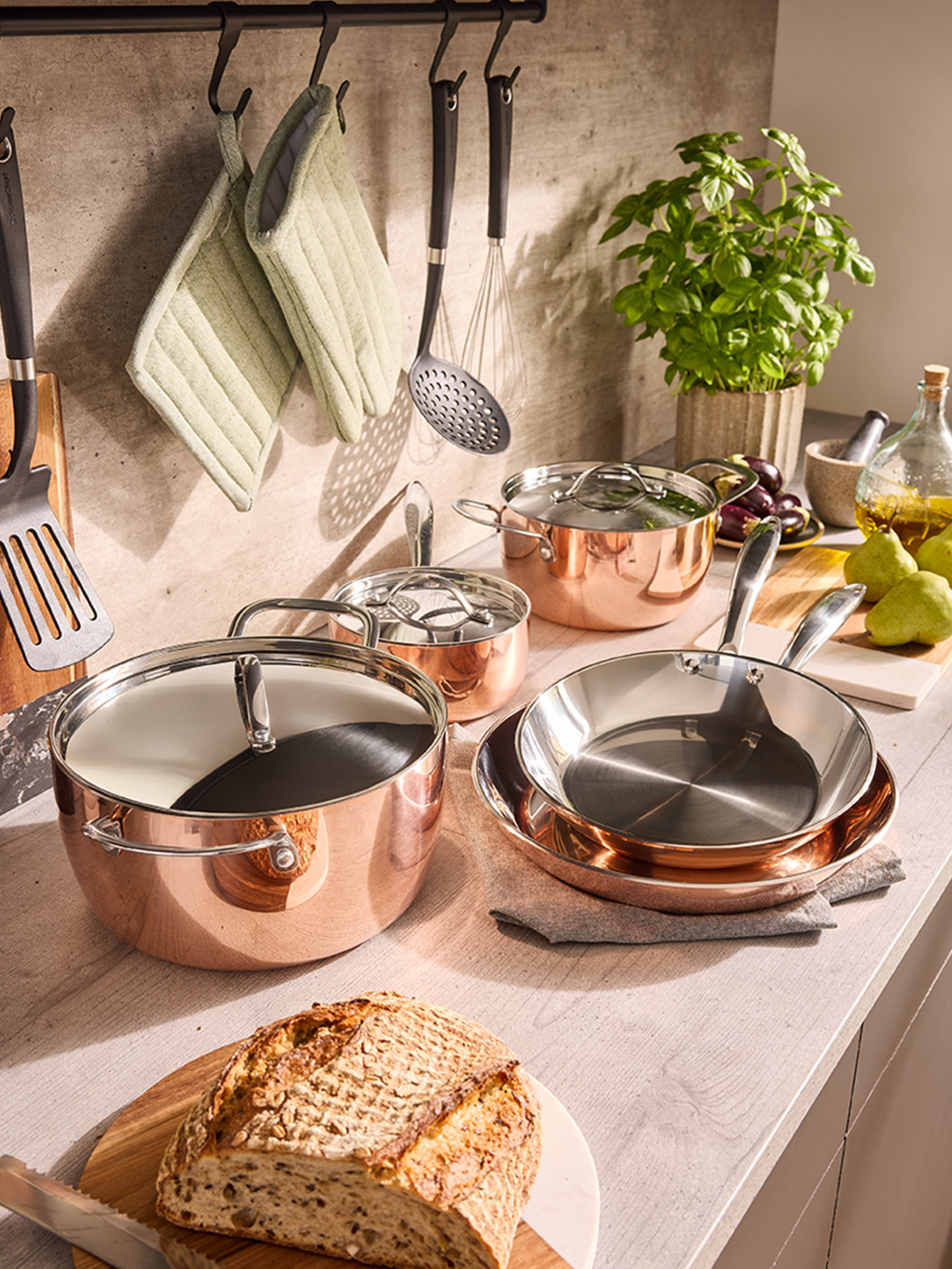 Set koperen kookgerei en pannen op een aanrecht, met brood en kruiden.