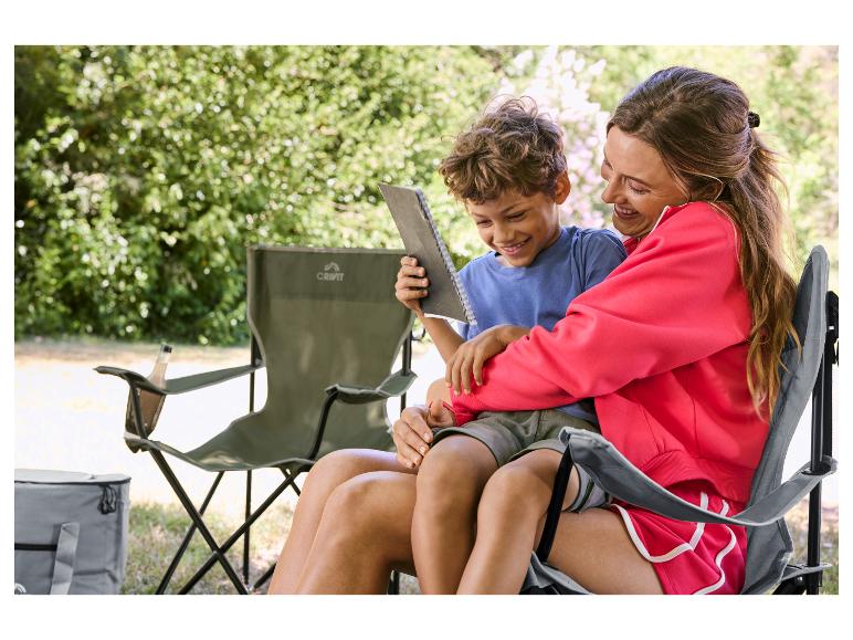 Vrouw en kind zitten op campingstoelen, buiten een boek lezend.