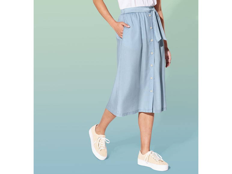 Een blauwe denim rok met knopen en een witte blouse.