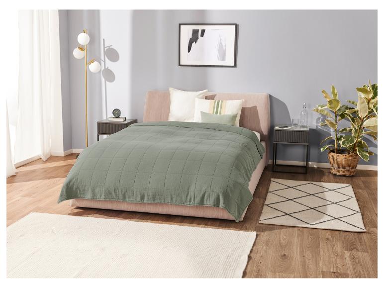 Olijfgroene deken op bed, tapijten en lampen.