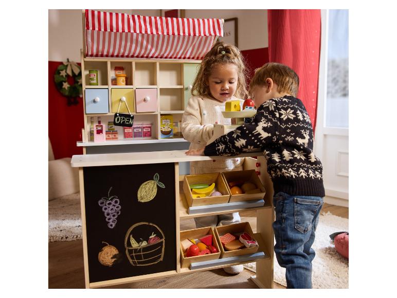 Twee kinderen spelen met een speelgoedmarkt met fruit, groenten en een weegschaal.