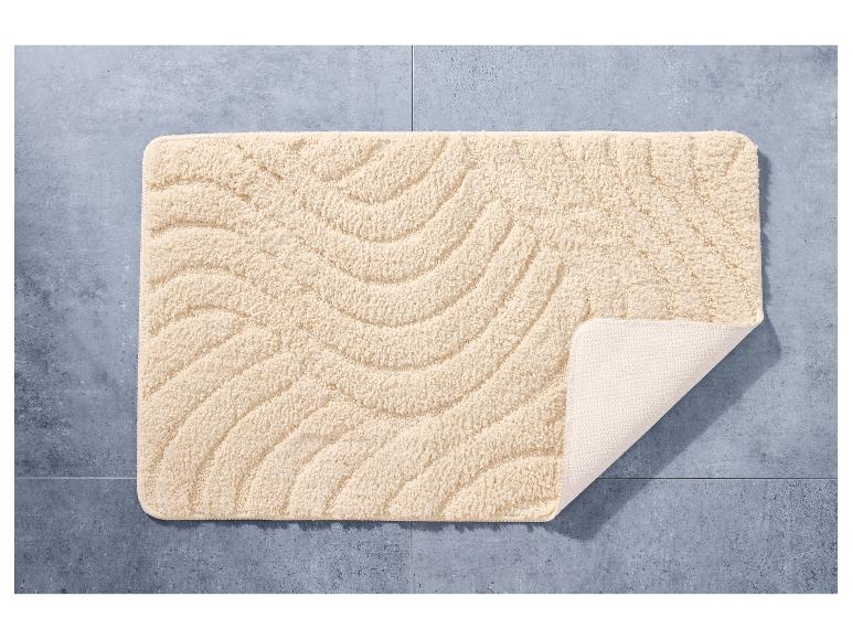 Een beige badmat met golvende textuur.
