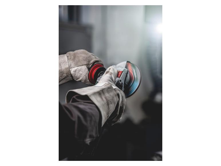 Gehandschoende handen houden een haakse slijper vast met een draaiende slijpschijf.