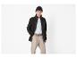 Man in zwart fleecejack, wit T-shirt, beige broek en zwarte muts.