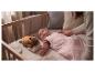 Baby in roze slaapzak met sterren, in wieg met een lichtgevend knuffeldier.