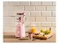Roze blender met fruit en smoothie op een houten tafel.