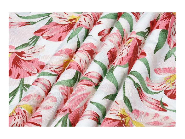 Witte stof met roze bloemen en groene bladeren, in plooien gedrapeerd.