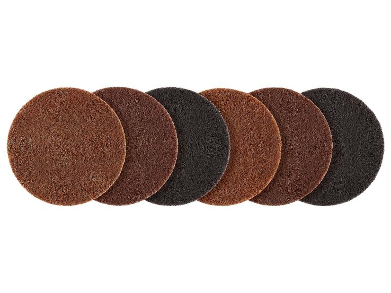 Zeven ronde schuurschijven in verschillende tinten bruin en zwart, op een rij.