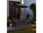 Tuinset met vier stoelen, tafel en parasol, verlicht met kerstverlichting.