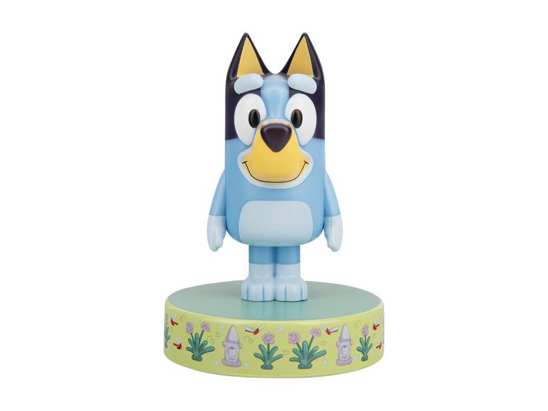 Blauwe cartoon hondenfiguur op een groene basis met een tuinthema.