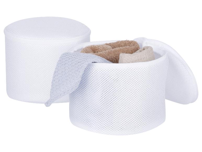 Twee witte waszakken van mesh, één gesloten en één open met handdoeken