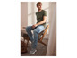 Man in groene T-shirt en blauwe jeans draagt casual schoenen.
