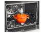 Oranje gietijzeren pan in een moderne oven op een metalen rooster.