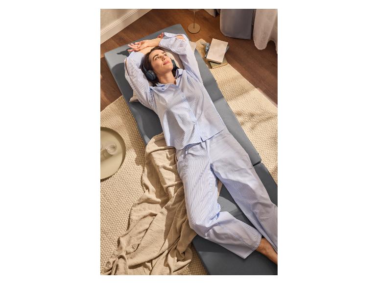 Vrouw ontspant zich op een opklapbed en luistert naar muziek.