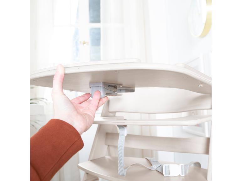 Hand die het mechanisme van een baby eetstoel aanpast.