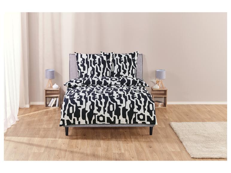 Een bed met zwart-wit gestreept beddengoed in een moderne slaapkamer.