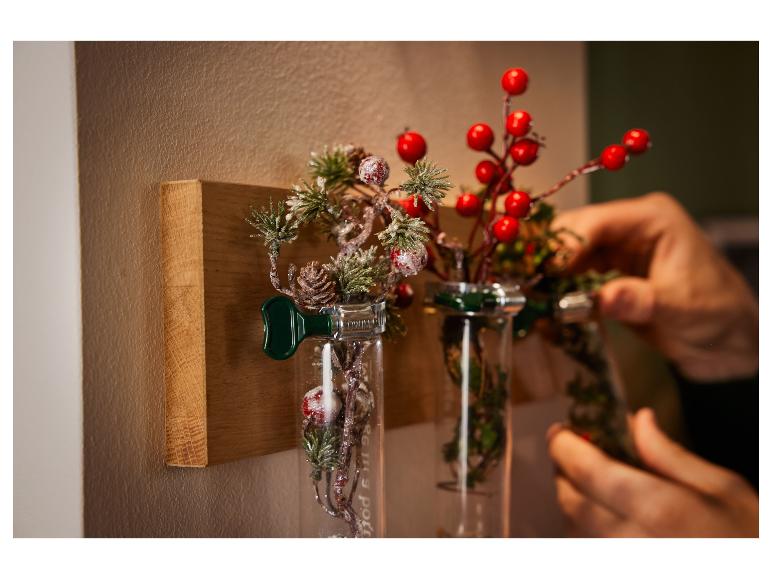 Kersttakken met rode bessen in glazen vazen met metalen clips.