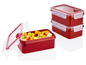 Drie rode plastic lunchboxen met fruit.