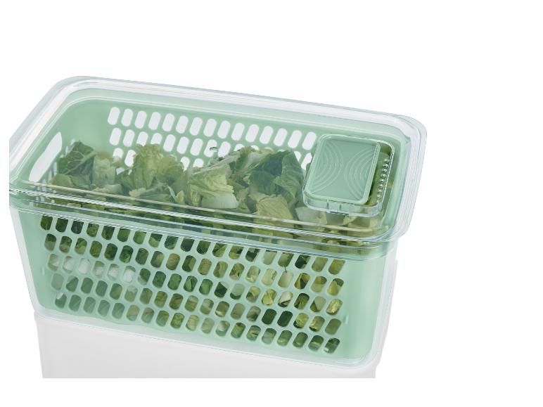 Groene plastic opbergdoos met een rooster erin, gevuld met sla.