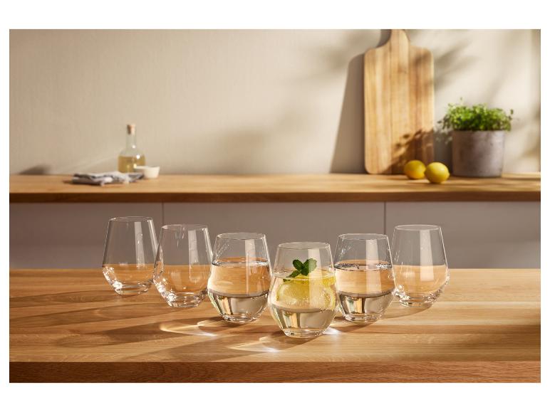 Zes glazen water op een houten tafel, één met citroen en munt.