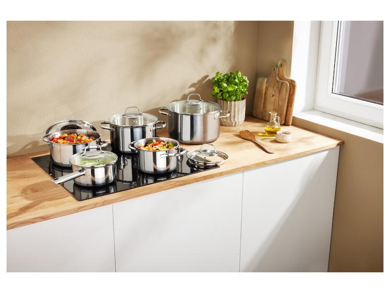 Set roestvrijstalen potten en pannen op een inductiekookplaat in een moderne keuken.