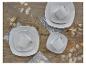 Drie sets wit, vierkant servies met kopjes op een houten tafel met decoratieve takken.