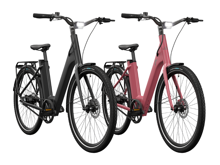 Twee moderne elektrische fietsen, één zwart en één roze, met geïntegreerde verlichting en riemaandrijving.