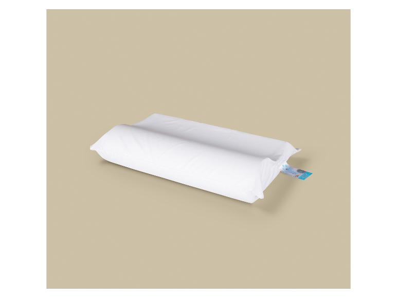 Wit orthopedisch kussen met blauw etiket op een beige achtergrond.