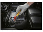 Een hand in een beschermende handschoen gebruikt een geïsoleerde schroevendraaier om de batterij van een auto los te maken.