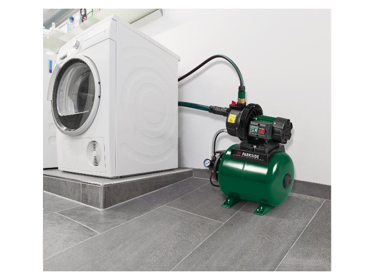 Groene huiswaterpomp aangesloten op een witte wasmachine in een wasruimte.