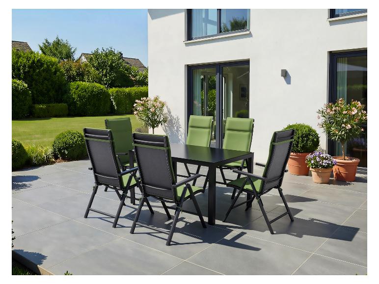 Buiten eethoek met zwarte tafel en groene stoelen op een terras naast een modern huis.
