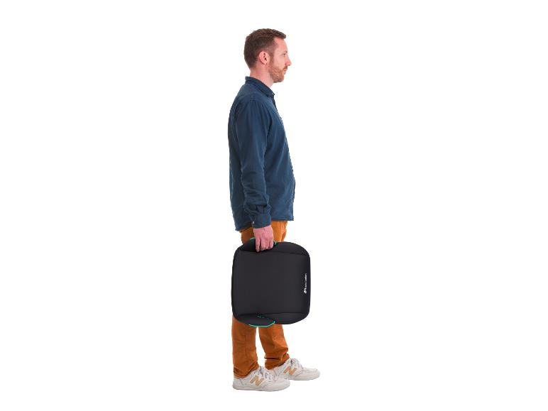 Man in overhemd en broek houdt een zwart kinderzitje vast.