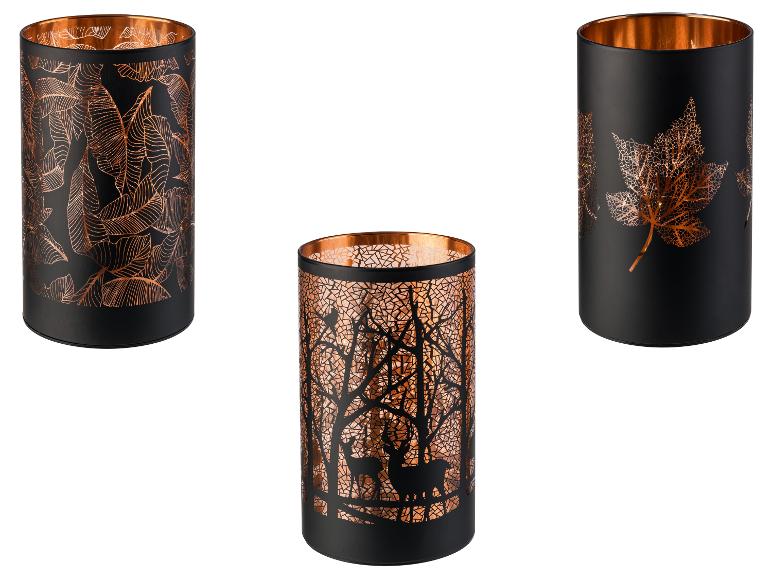 Drie zwarte kaarsenhouders met koperen details en verschillende patronen.