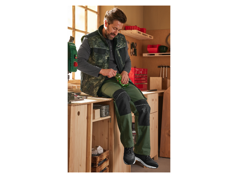 Een man in een werkplaats draagt Parkside werkkleding en drinkt uit een fles.