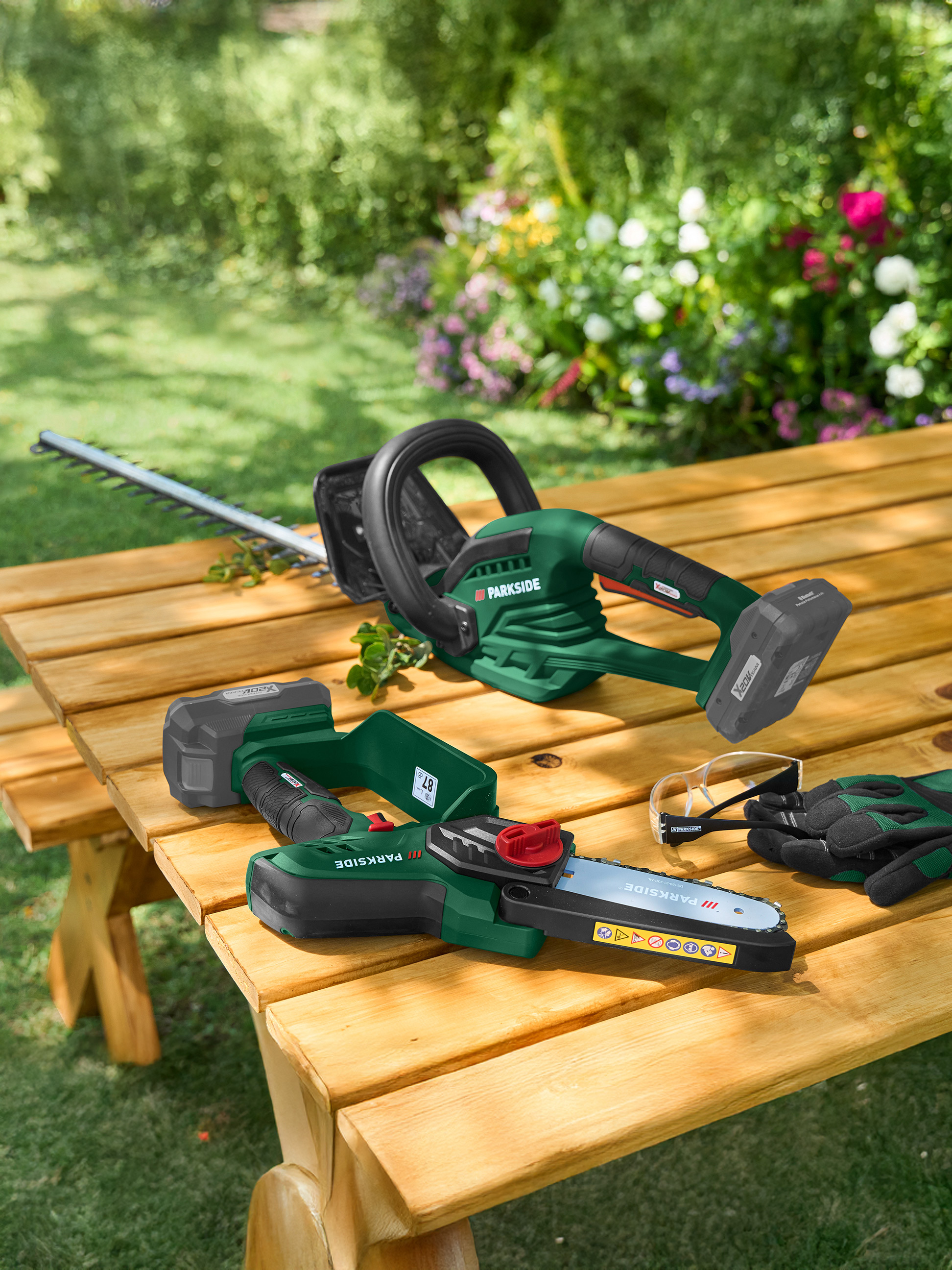 Heggenschaar en kettingzaag op een houten tafel in de tuin