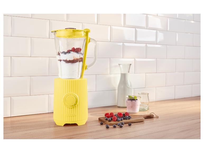 Gele blender met yoghurt en bessen op een aanrecht.