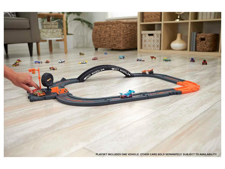 Hot Wheels racebaan met meerdere speelgoedauto's op een houten vloer.