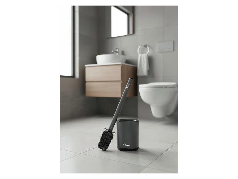 Grijze toiletborstel met houder in een moderne badkamer.