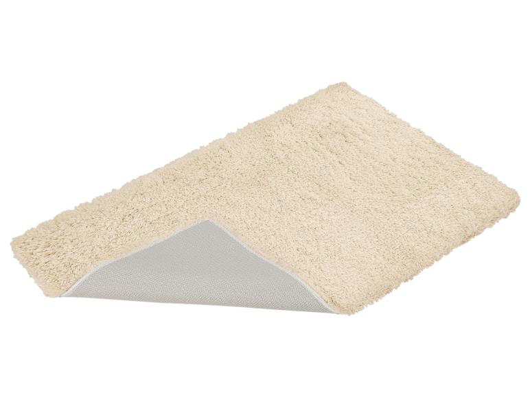 Crèmekleurig badmatje met antislip onderkant, schuin liggend.