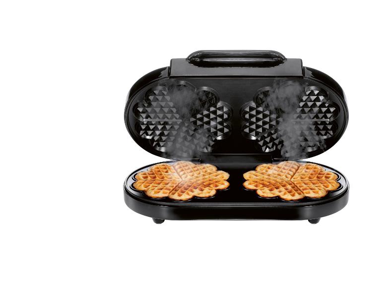 Zwart wafelijzer met twee hartvormige wafels en stoom