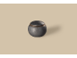 Bolvormige donkere metalen urn met deksel, op een beige achtergrond.