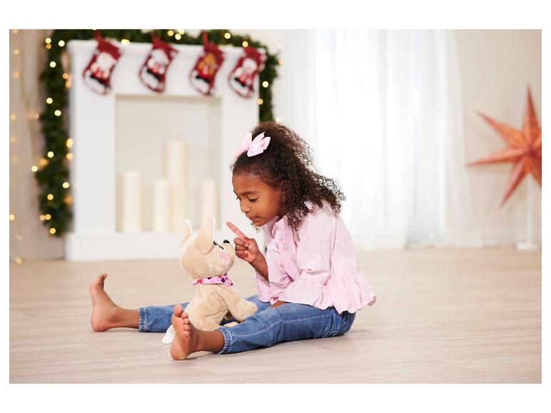 Een meisje speelt met een knuffelpuppy voor de open haard met kerst.