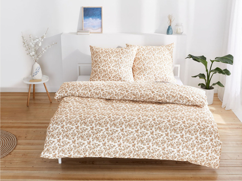 Een bed met een wit dekbedovertrek met een klein bloemenpatroon.