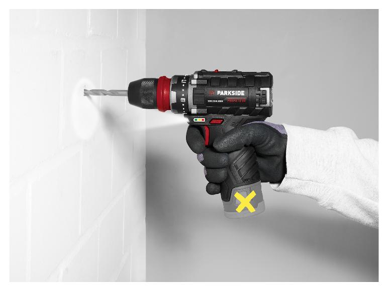 Accuboormachine met boor maakt een gat in een witte bakstenen muur, vastgehouden door een gehandschoende hand.