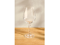 Leeg wijnglas op een houten tafel met een lichte muur op de achtergrond.