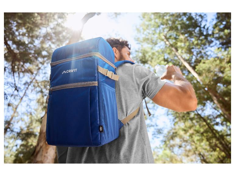 Man met blauwe koelrugzak drinkt water in een bos.