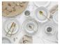 Grijs-wit keramisch servies met gouden bestek, linnen en natuurlijke decoraties.