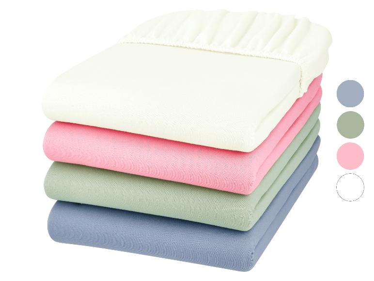 Stapel pastelkleurige hoeslakens: beige, roze, groen en blauw.