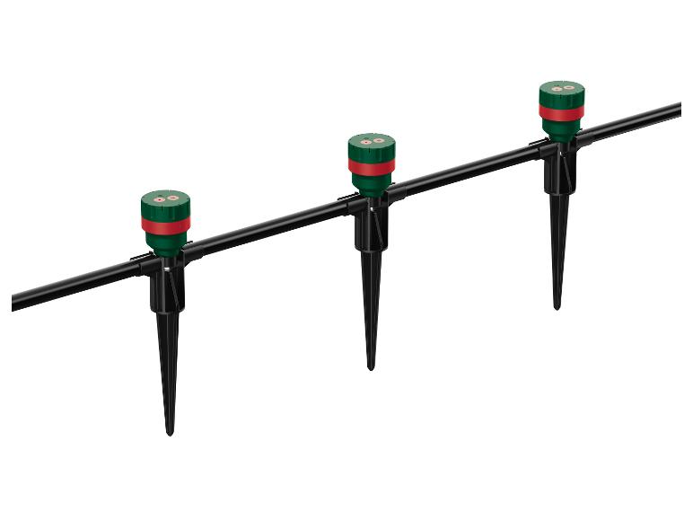 Drie groene en rode tuinsproeiers op zwarte pinnen verbonden door een zwarte pijp.